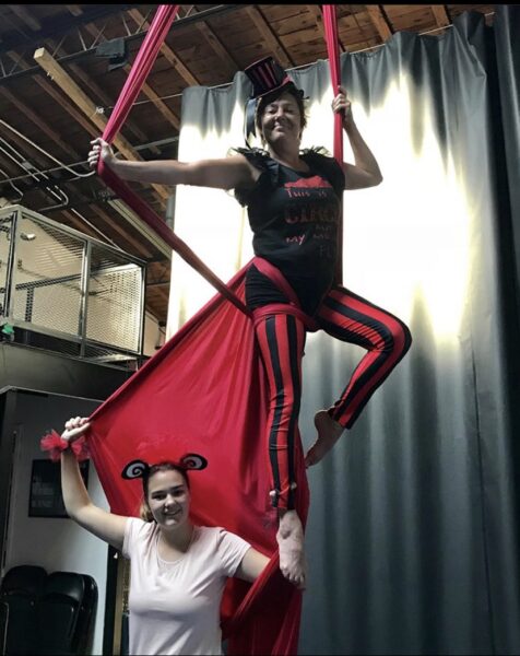 Young girl standing beside aerial artist.