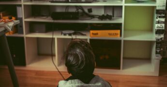 Kid sitting in floor playing a video game on television.