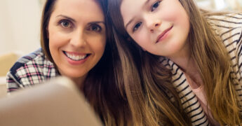 Portrait of mother and daughter using laptop in living room at home
