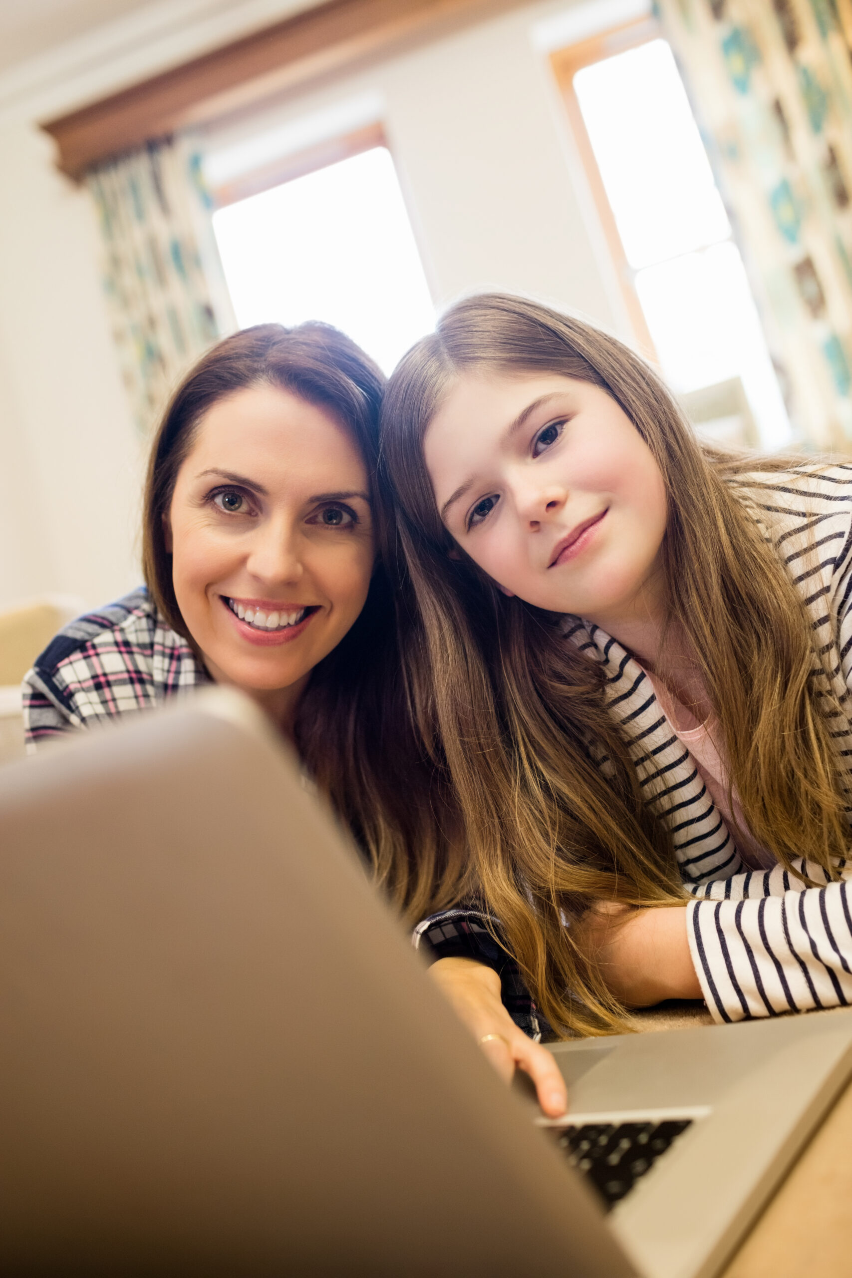 Portrait of mother and daughter using laptop in living room at home