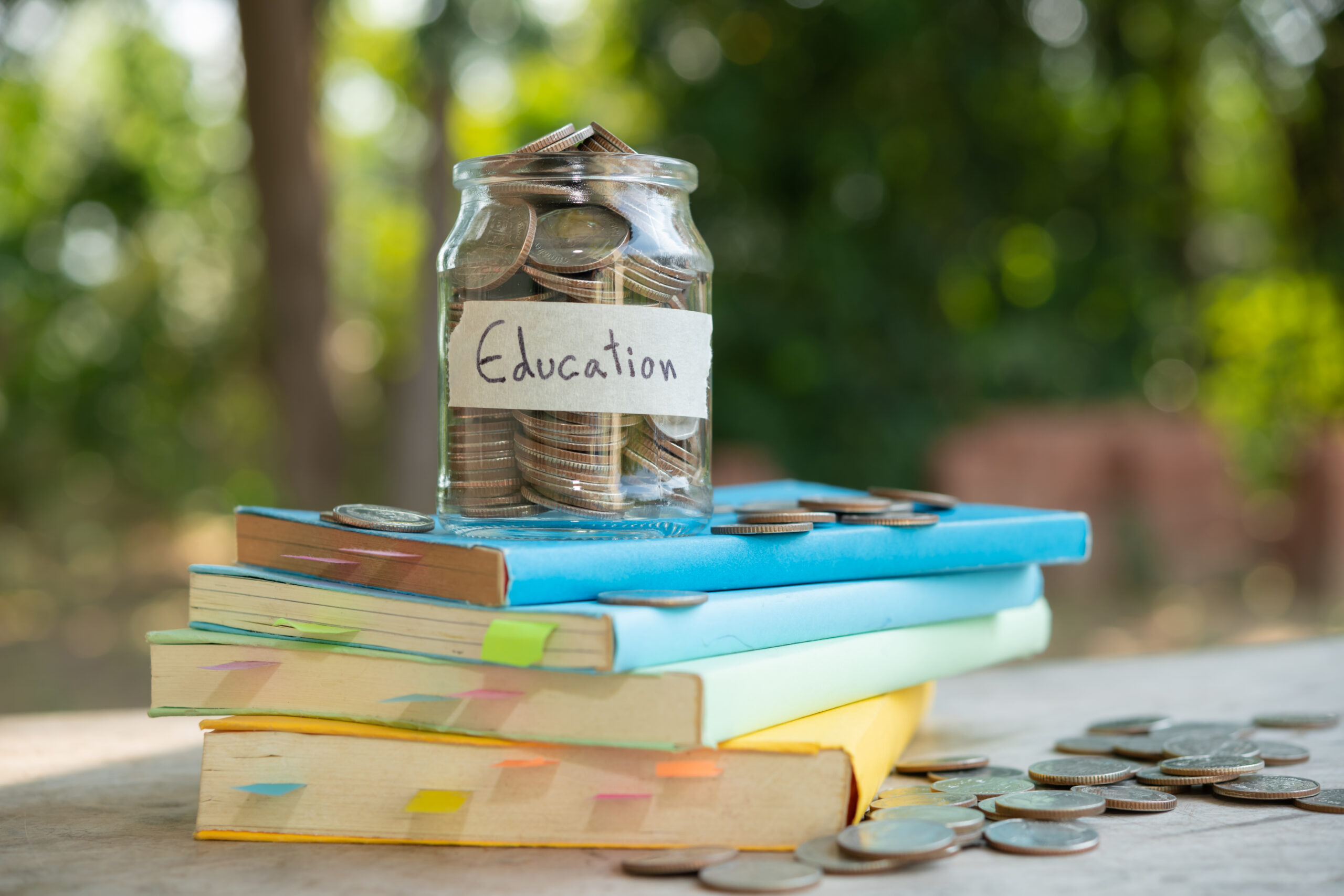 Money in jar labeled "education" on a stack of books.