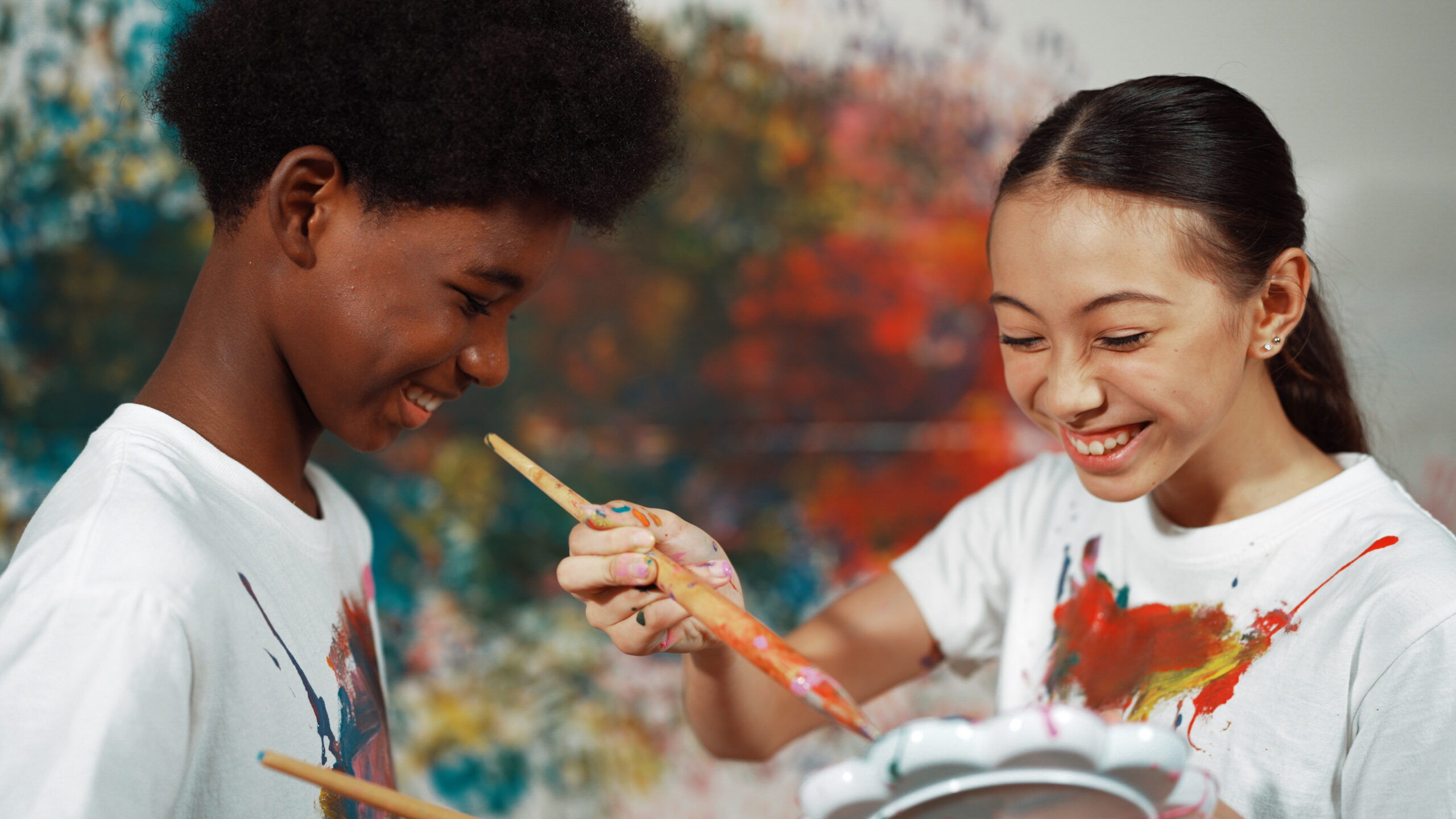 two students smiling and painting